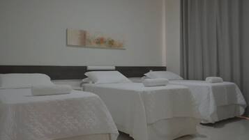 Quarto de hotel com duas camas, uma janela grande com cortinas e um quadro na parede.