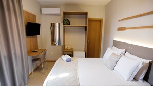 A hotel room with a bed, a desk, a chair, a television, a wardrobe, and a small table. - Mar de Canasvieiras Hotel & Eventos (Florianópolis)