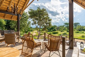 Un espacio de estar al aire libre cubierto, con mobiliario de mimbre y vistas del paisaje circundante.