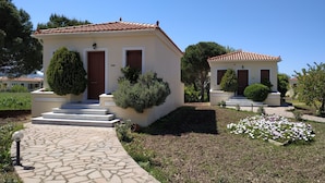 Two small, single-story buildings with tiled roofs and white walls, each with a front door and steps leading to the entrance. - Gaea Gardens Studios (Lesvos)