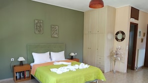 A neatly arranged bedroom with a bed, bedside tables, a wardrobe, and a mirror. - Gaea Gardens Studios (Lesvos)