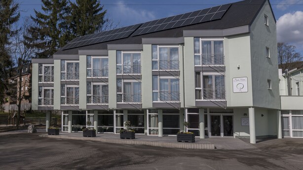 Un hotel moderno con varios pisos, ventanas amplias y paneles solares en el techo.