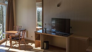 Una habitación moderna con un escritorio de madera, un televisor de pantalla plana, una silla y una planta en maceta.