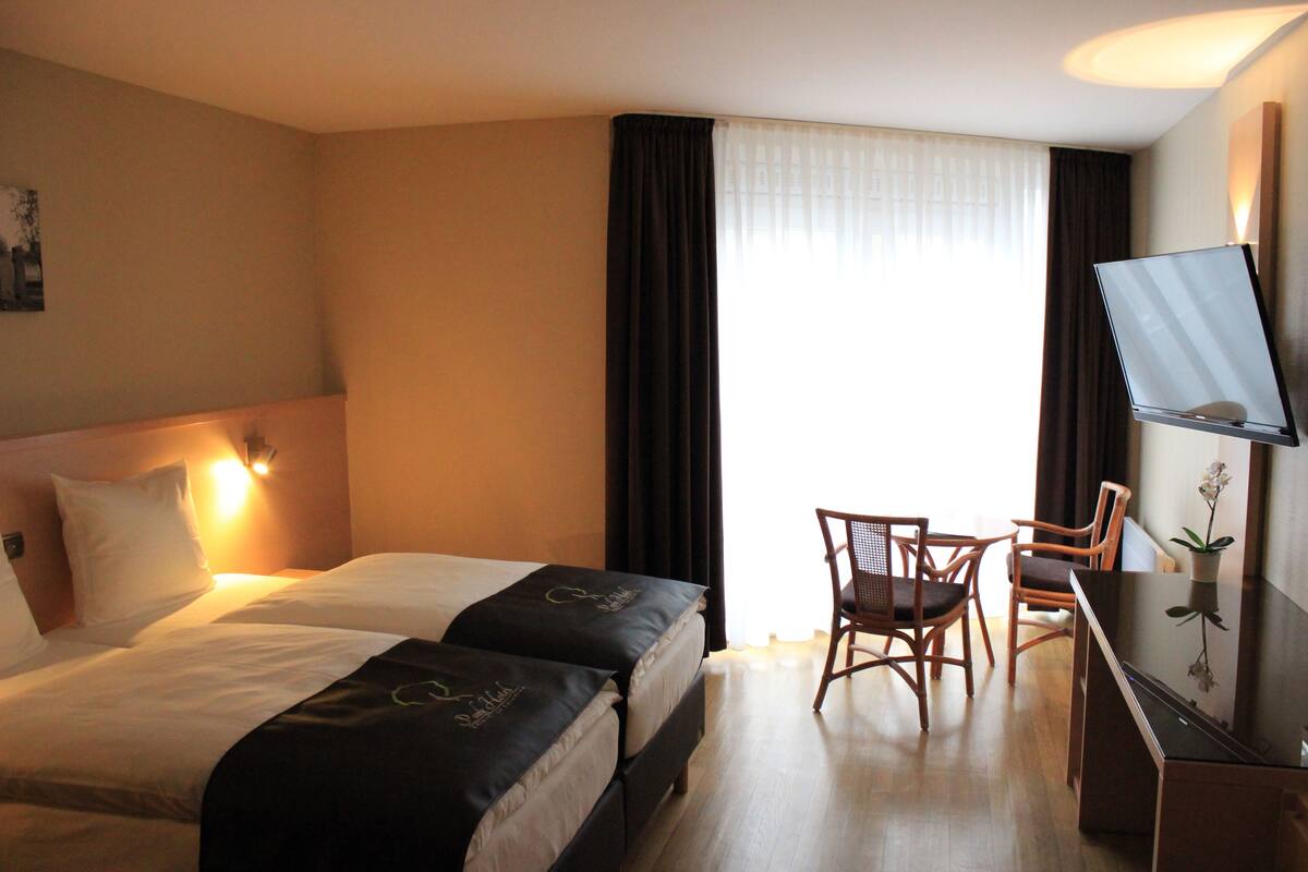 A hotel room with two beds, a desk, and a chair.