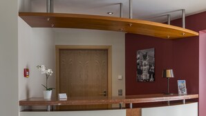 Un mostrador de recepción con tapa de madera, una orquídea en maceta y una fotografía enmarcada en la pared.