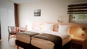 Una cama doble con cabecera, mesitas de noche, una silla y una pequeña mesa.