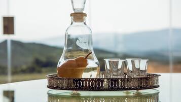 A clear glass decanter with a cork stopper, a metal tray with a decorative pattern, and four clear glasses on the tray.