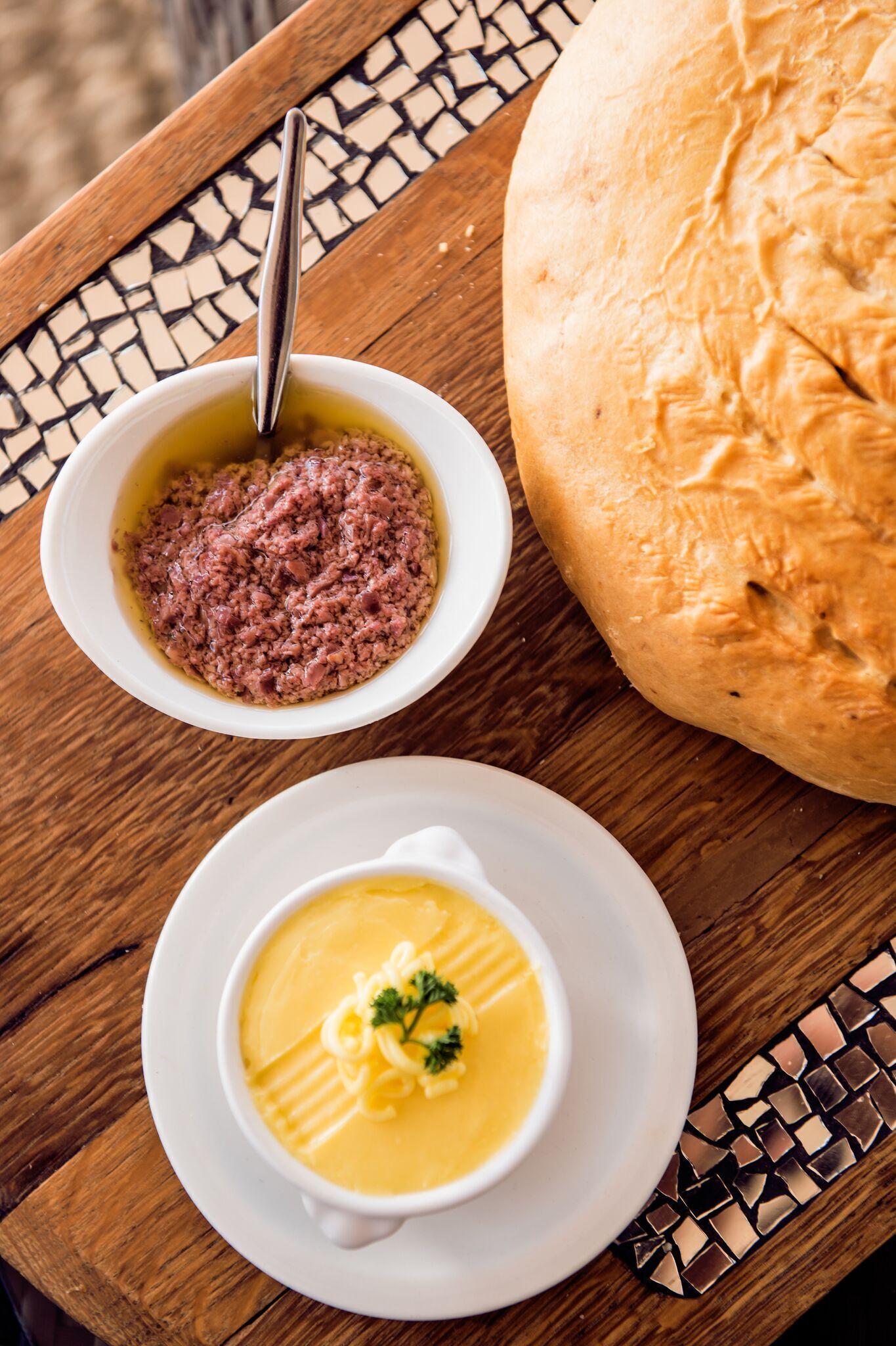 Una mesa con un tazón de sopa, un tazón de salsa y una hogaza de pan.