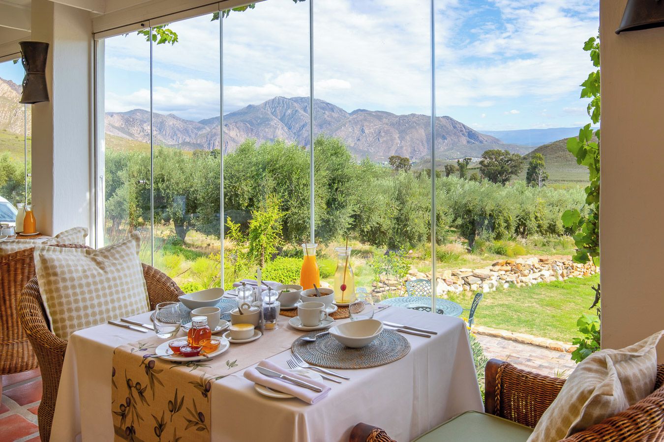 A dining area with a table set for breakfast, overlooking a mountainous landscape.