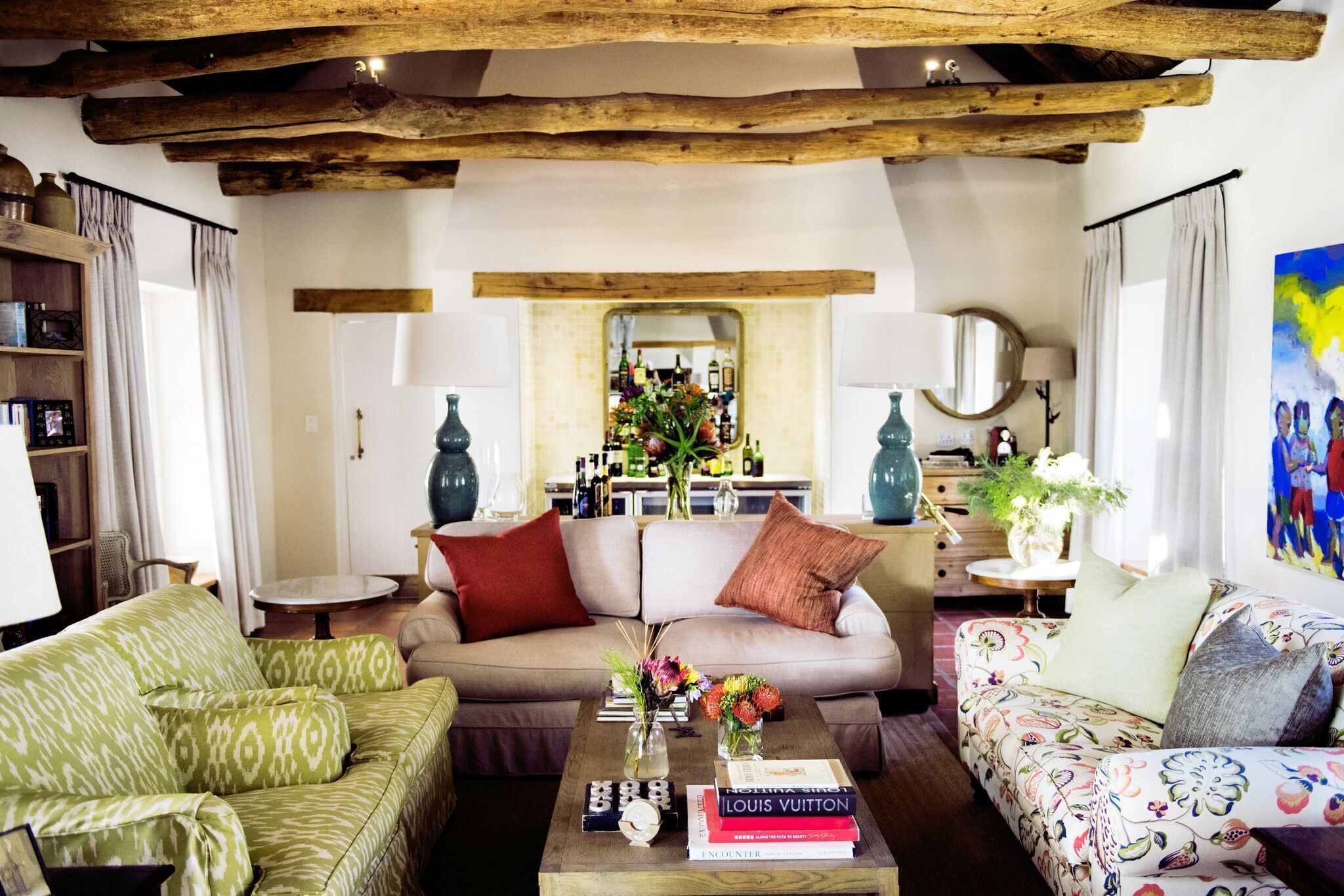 Una sala de estar acogedora con un sofá, una mesita de centro con libros y flores, y un techo de madera.