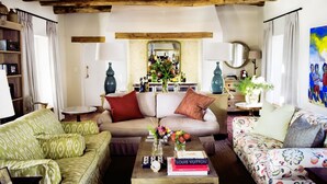 A cozy living room with a sofa, a coffee table with books and flowers, and a wooden ceiling. - Galenia Estate (Montagu)