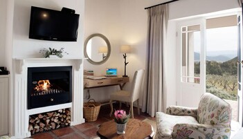 Una habitación acogedora con chimenea, un escritorio con un ordenador portátil, un sillón cómodo y un televisor en la pared.