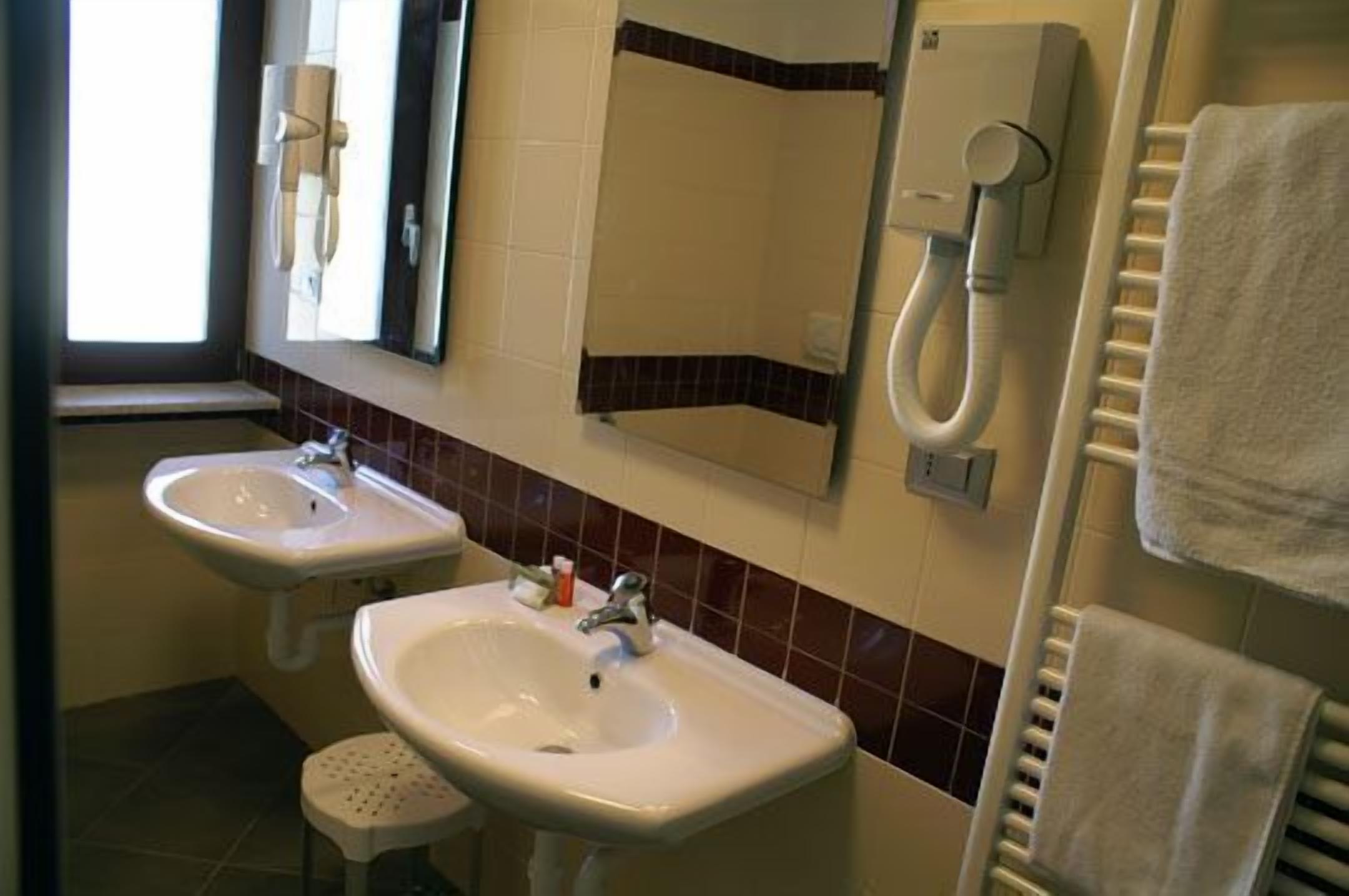 A bathroom with two sinks, a mirror, a towel rack, and a window.