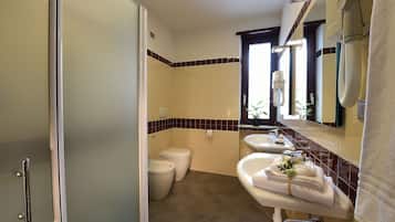 Un bagno con doccia, toilette, lavandino e portasciugamani con asciugamani.