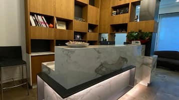 A modern kitchen with wooden cabinetry, a marble island, and pendant lighting.