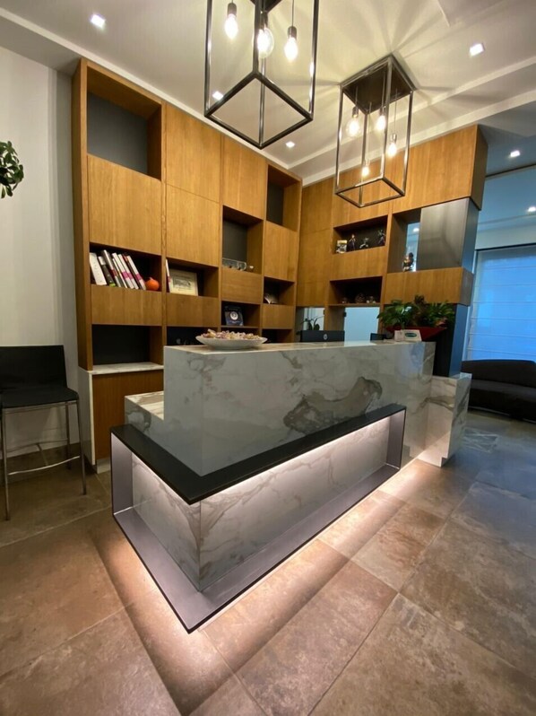 A modern kitchen with wooden cabinetry, a marble countertop, and pendant lighting.