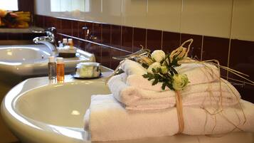 Ein Badezimmer mit zwei Waschbecken, Toilettenartikeln und ordentlich gefalteten Handtüchern sowie einer dekorativen Blumenkomposition.