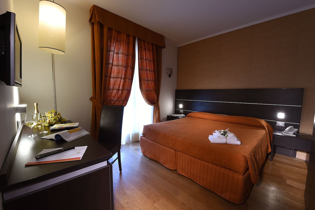 Una habitación de hotel con cama, escritorio, lámpara y teléfono.