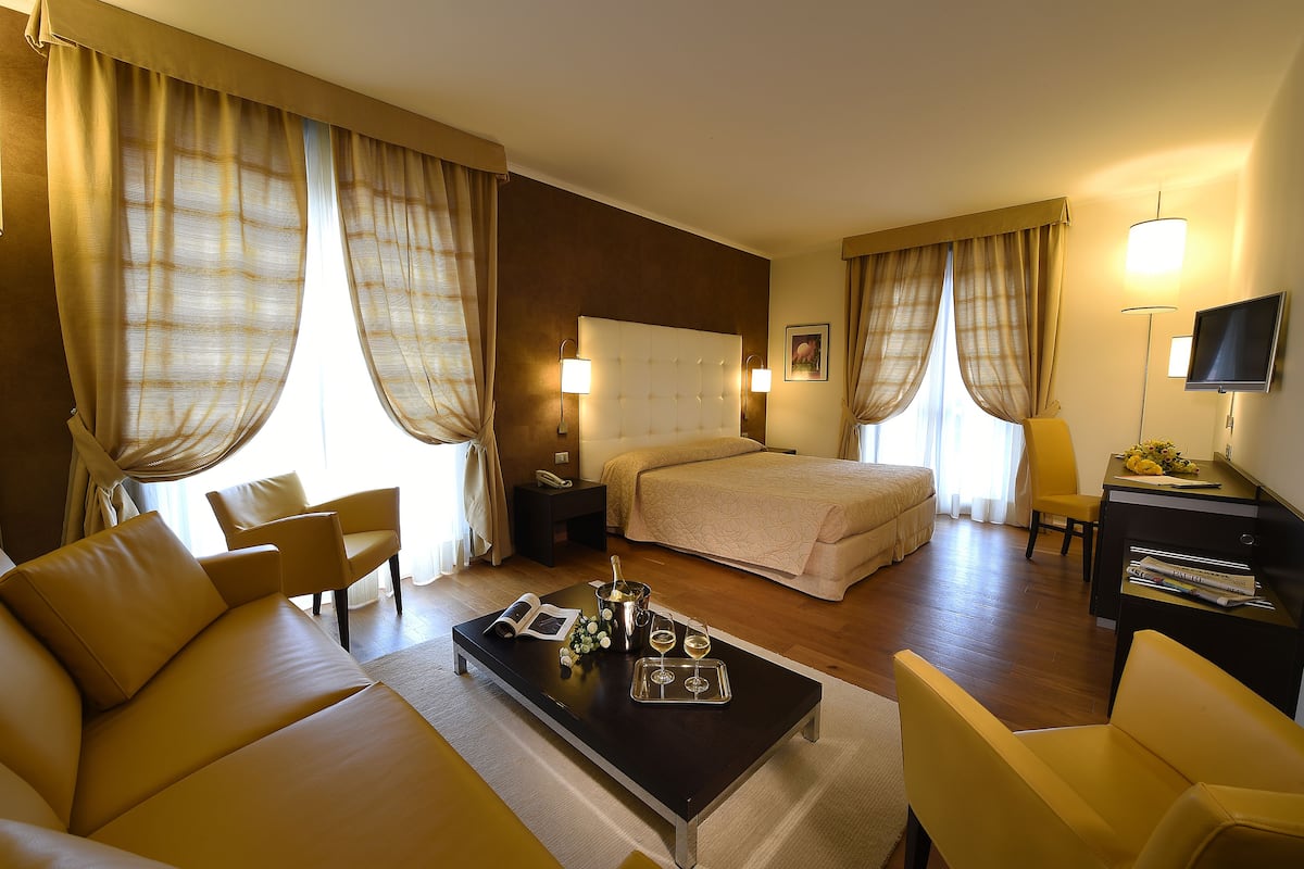 Una habitación de hotel con cama, sofá, escritorio y televisión.