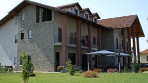 Un edificio de varios pisos con fachada de piedra, balcones y una zona de estar al aire libre cubierta.
