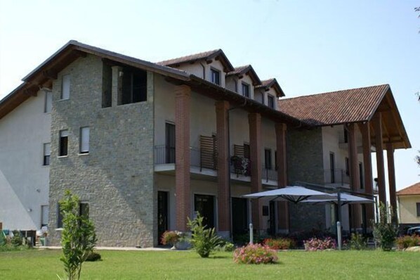 A multi-story building with a stone facade, balconies, and a covered outdoor seating area.