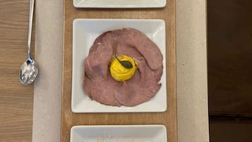 Three square plates of food on a wooden table.