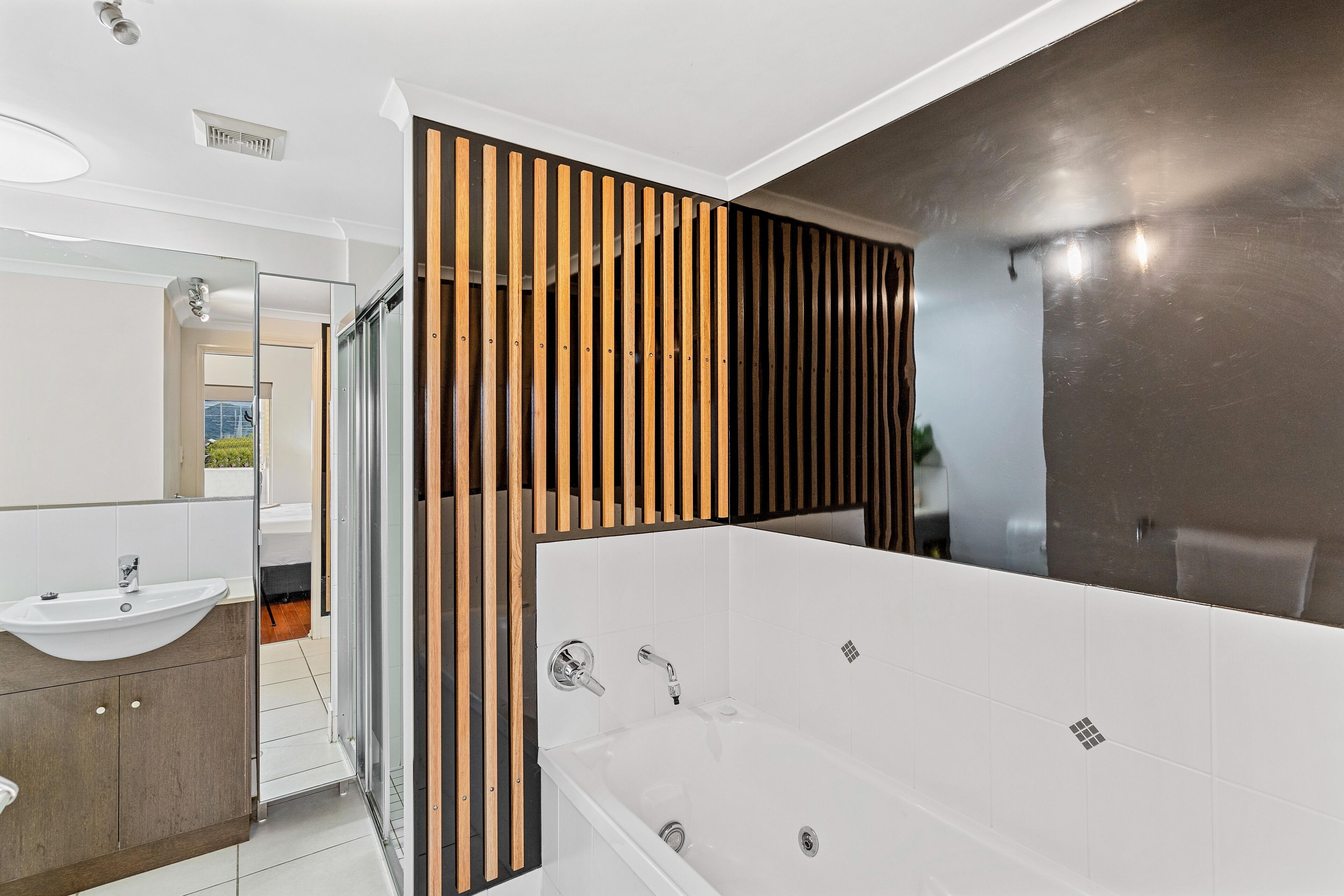 Un bagno moderno con un lavandino bianco, una vasca e uno spazio doccia.