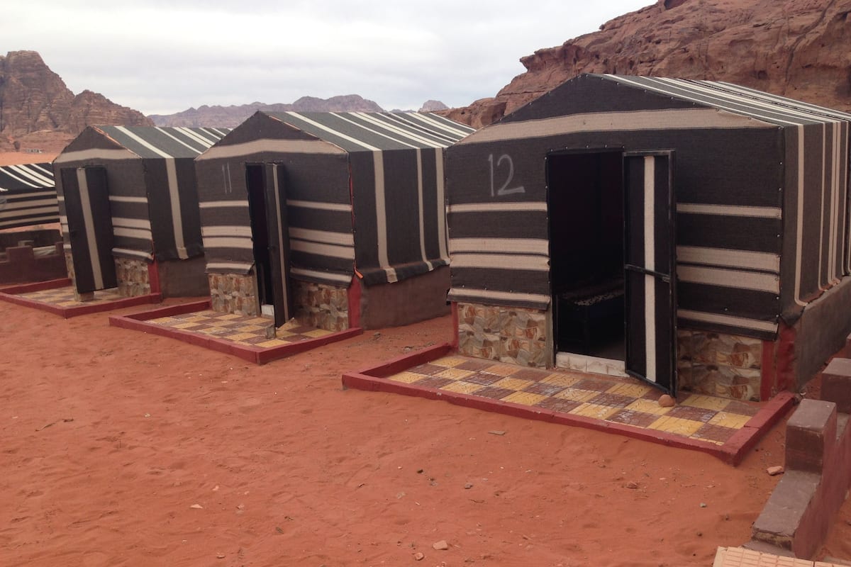 Fila de cabañas individuales con rayas y números, ubicadas en un paisaje desértico.