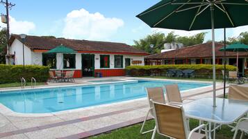 Una piscina al aire libre, sombrillas, sillones reclinables de piscina