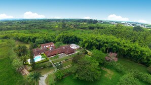 Une vue aérienne d’un vaste domaine comprenant plusieurs bâtiments, une piscine et de vastes espaces verts.