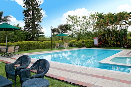 Una piscina al aire libre, sombrillas, sillones reclinables de piscina