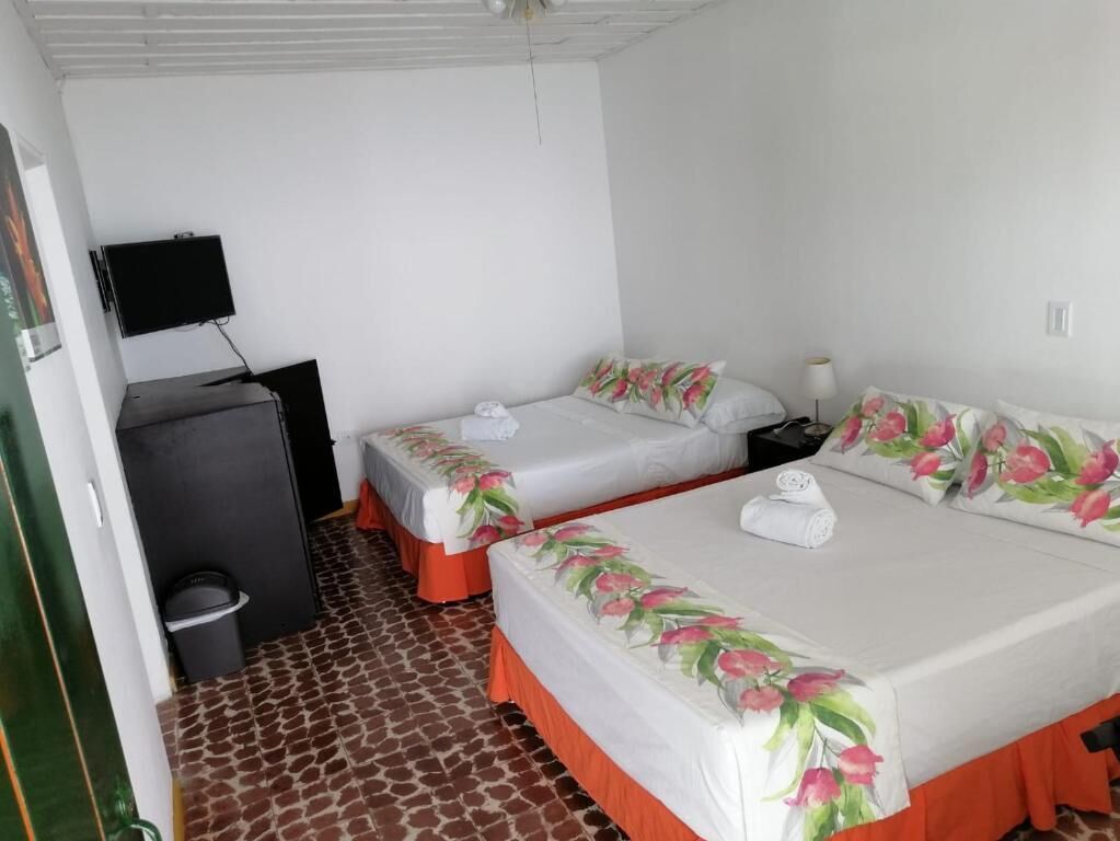 A hotel room with two beds, a TV, a desk, and a trash bin.