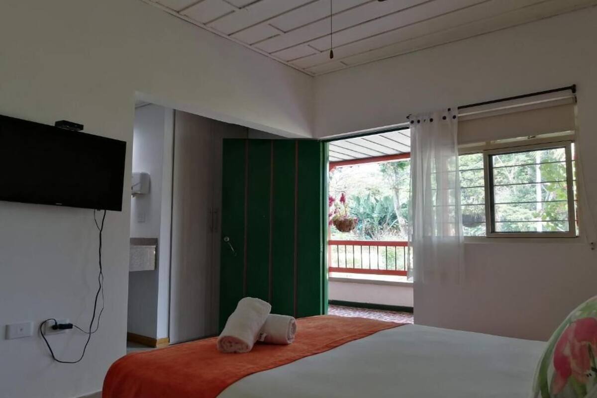 Een hotelkamer met een bed, een aan de muur bevestigde televisie en een raam met gordijnen.