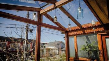 Una habitación con estructura de techo de madera, ventanas amplias y lámparas colgantes.