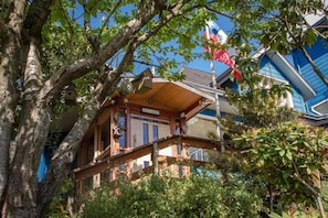 A wooden cabin with a balcony, surrounded by trees and a clear sky. - Casa Kalfu (Puerto Varas)