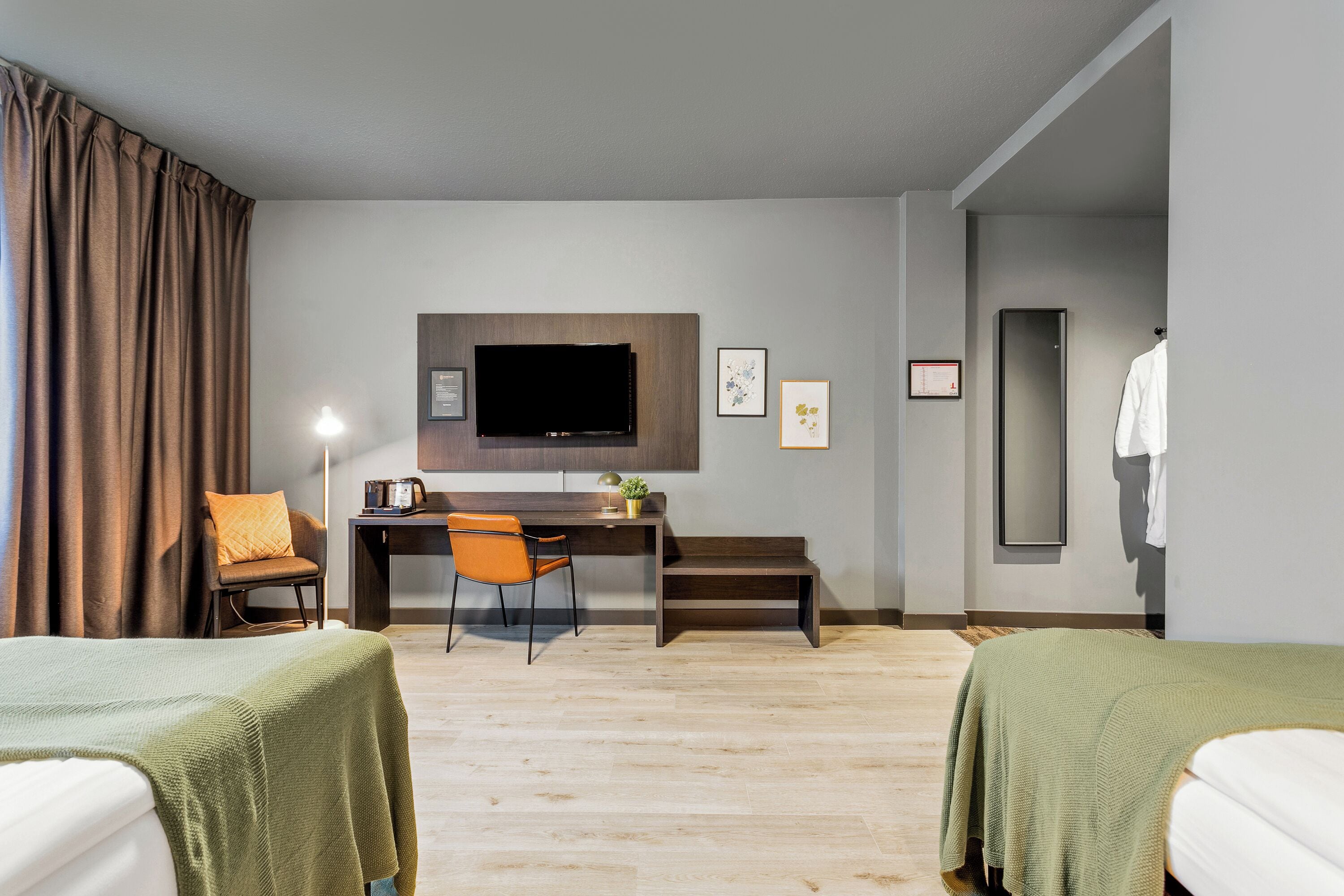 A hotel room with two beds, a desk with a chair, a television, and artwork on the wall.