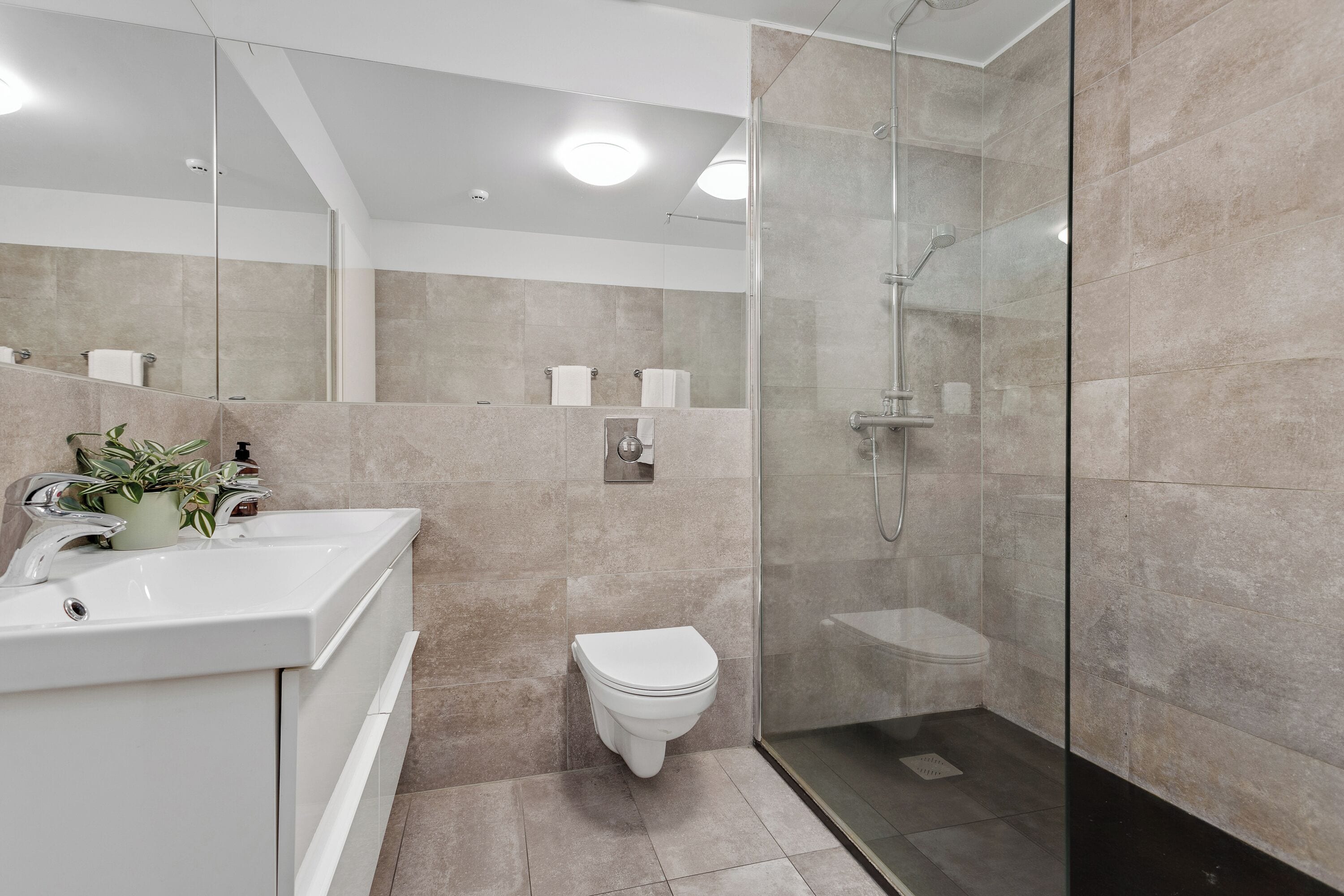 Un baño moderno con ducha de vidrio, lavamanos blanco y un inodoro.