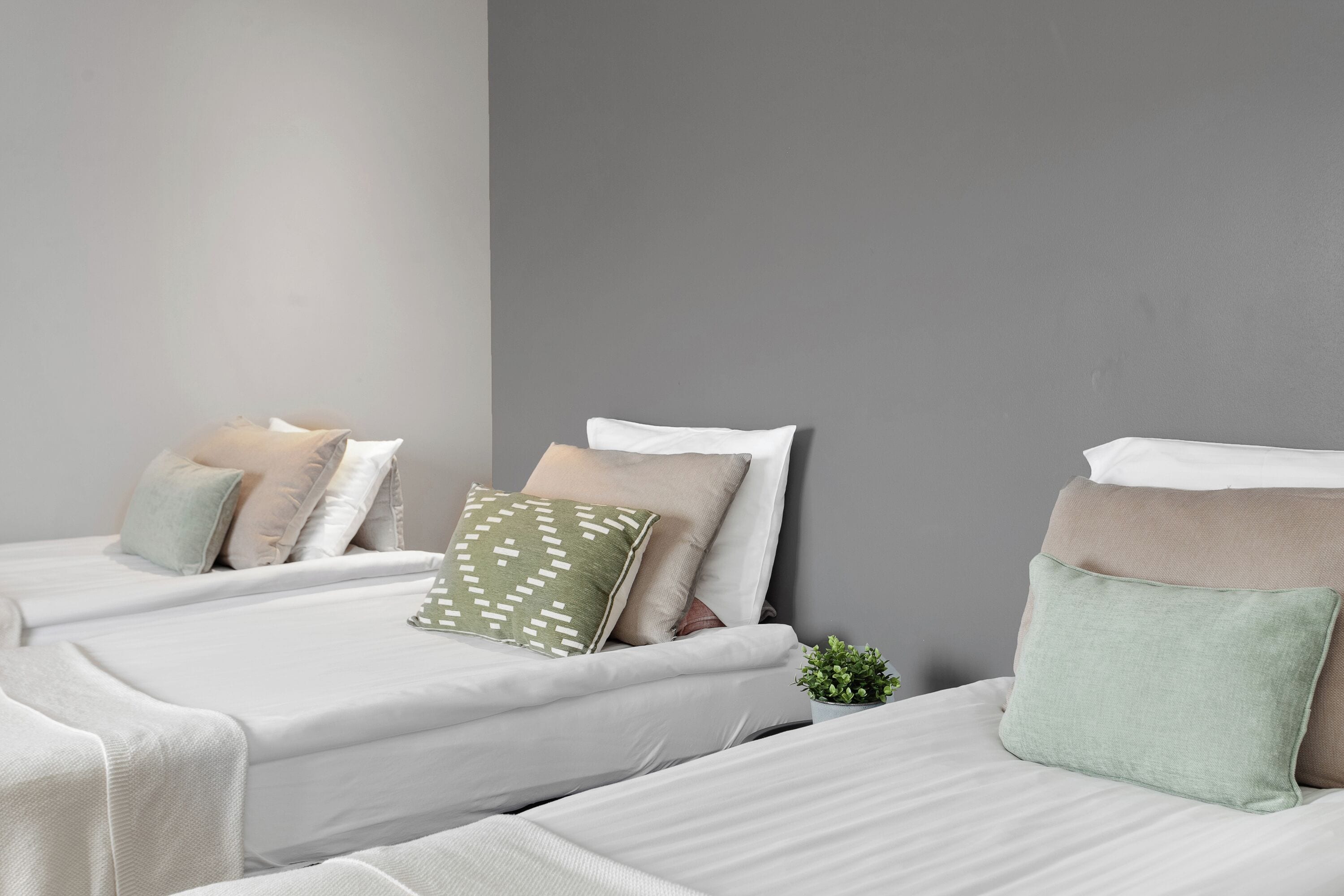 Ein Hotelzimmer mit zwei Betten, jeweils mit weißer Bettwäsche und mehreren Kissen.
