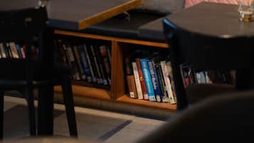 A cozy reading nook with a cushioned bench, a small table, and a bookshelf filled with books.