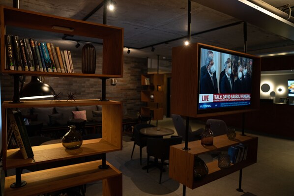 A modern interior with wooden shelves, a television displaying a news broadcast, and a cozy seating area.