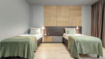 A modern bedroom with two beds, a wooden headboard, and a bedside table with a lamp.