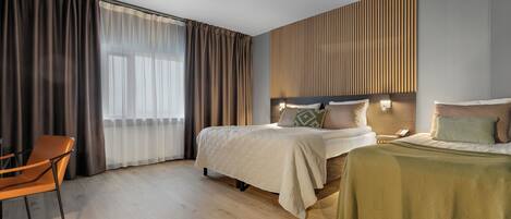 Una habitación de hotel con una cama, una silla y un ventanal con cortinas.