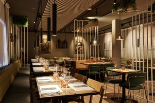 Un restaurante con mesas comunitarias largas, cabinas individuales y lámparas colgantes.