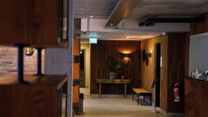 A hallway with wooden walls, a bench, a table with a plant, and a fire extinguisher. - Konvin Hotel by Reykjavik Keflavik Airport (Reykjanesbær)