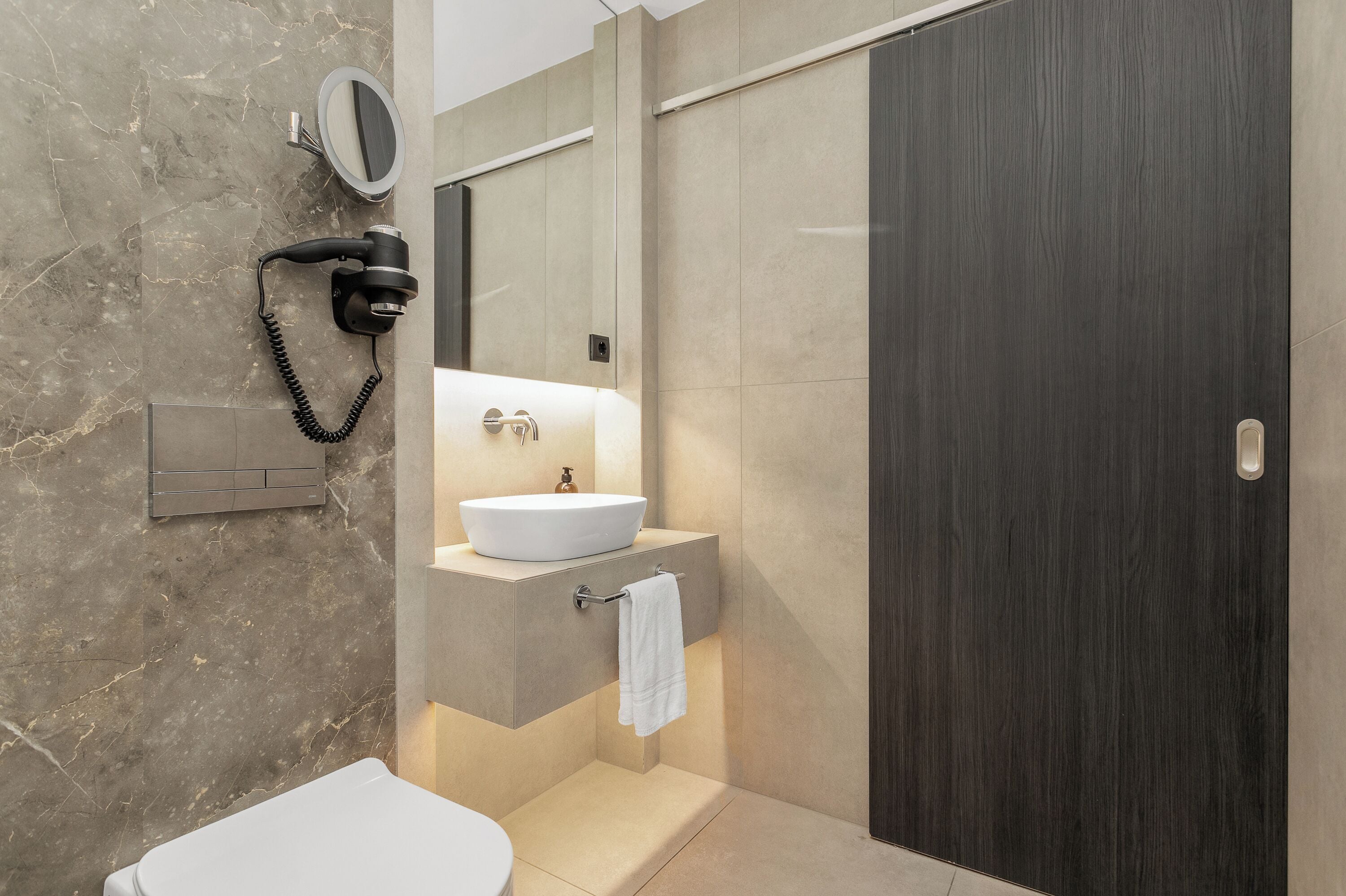 A modern bathroom with a built-in sink, a hairdryer, and a mirror.