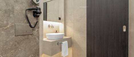 A modern bathroom with a built-in sink, a hairdryer, and a mirror.