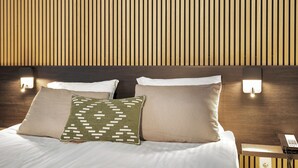 A neatly made bed with two pillows, a bedside table with a phone, and a wall with vertical wooden slats. - Konvin Hotel by Reykjavik Keflavik Airport (Reykjanesbær)