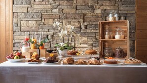 A buffet table with various food items and a stone wall background. - Hotel Don Luis (Castel di Sangro)