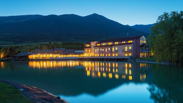 A hotel with a large building reflecting on a calm lake, surrounded by mountains. - Hotel Don Luis (Castel di Sangro)