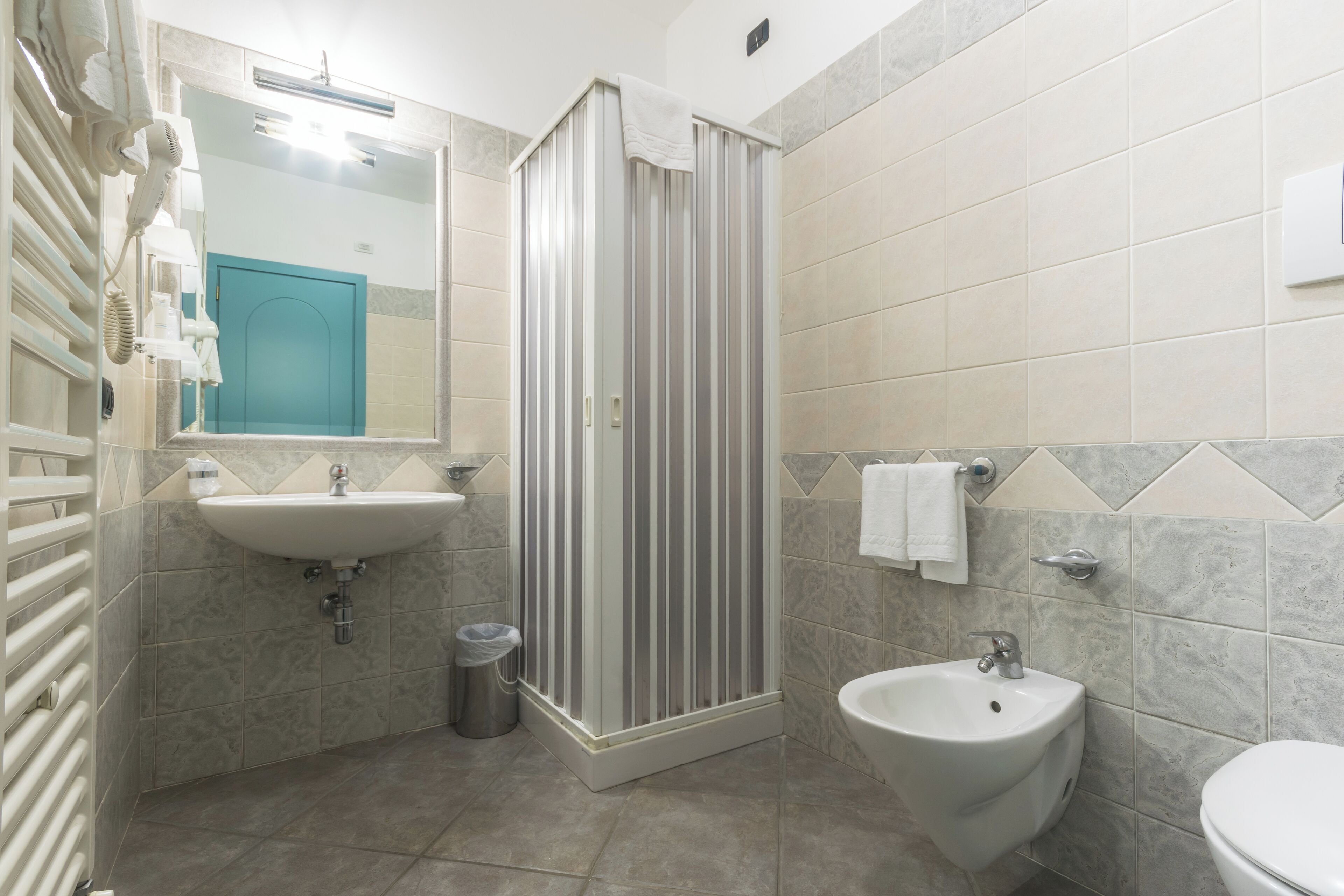 A bathroom with a shower, sink, and bidet.